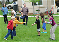 A bunch of chlidren playing, as two adults look on